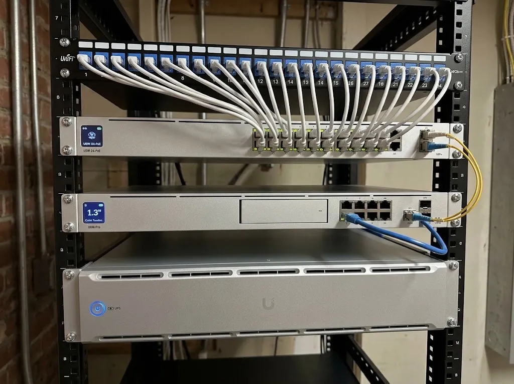A network rack with a labeled patch panel, switch, gateway, and battery backup